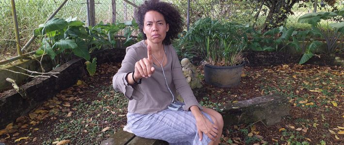 Karina Jap a Joe die zittend in de tuin boos kijkt en bestraffend haar vinger omhoog houdt